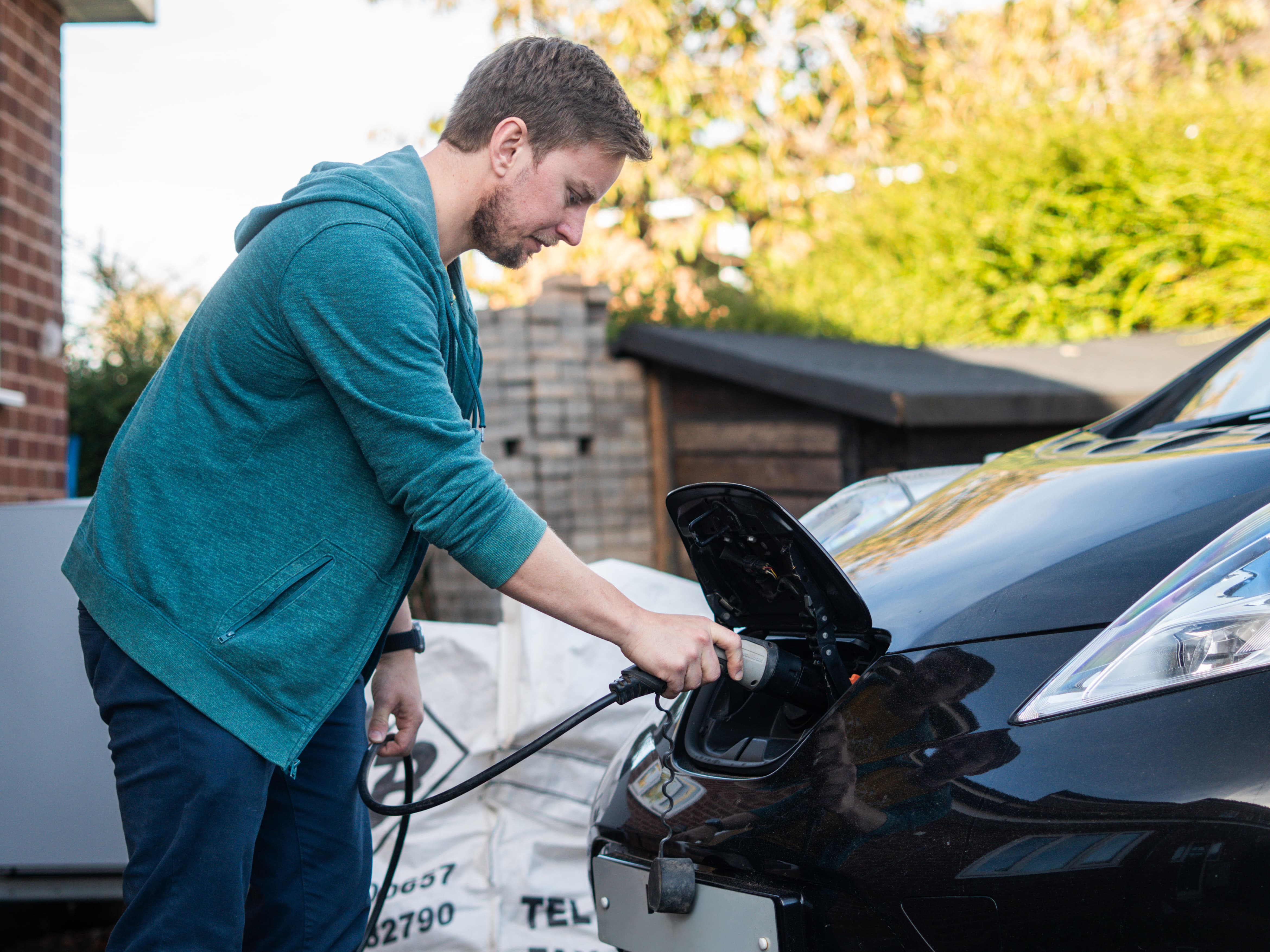 a man plugging an EV charger to an electric vehicle