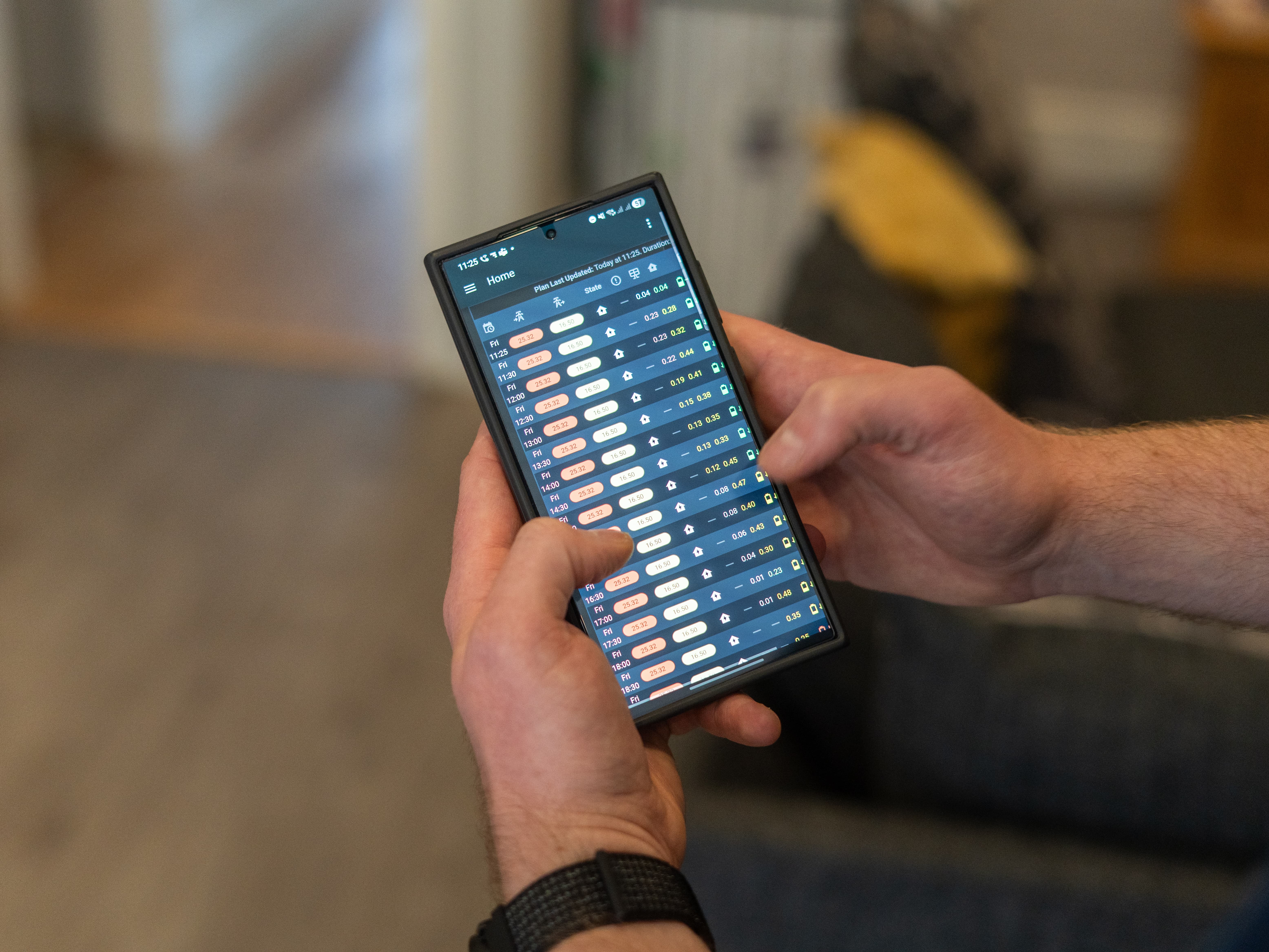 someone holding a smartphone showing energy consumption data on the screen